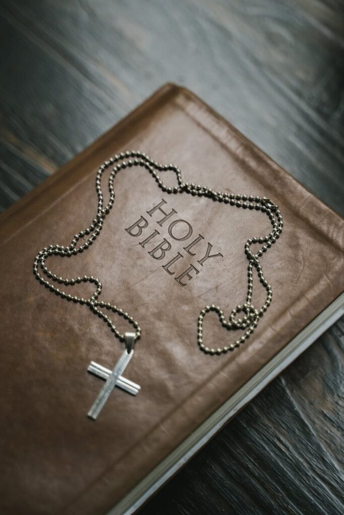 silver cross pendant necklace on brown holy bible